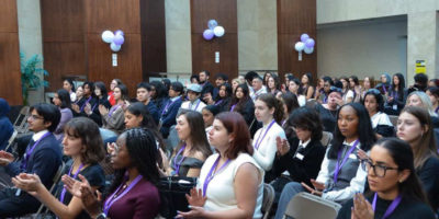 Photo of a crowd sitting while clapping at a Pen For Justice event