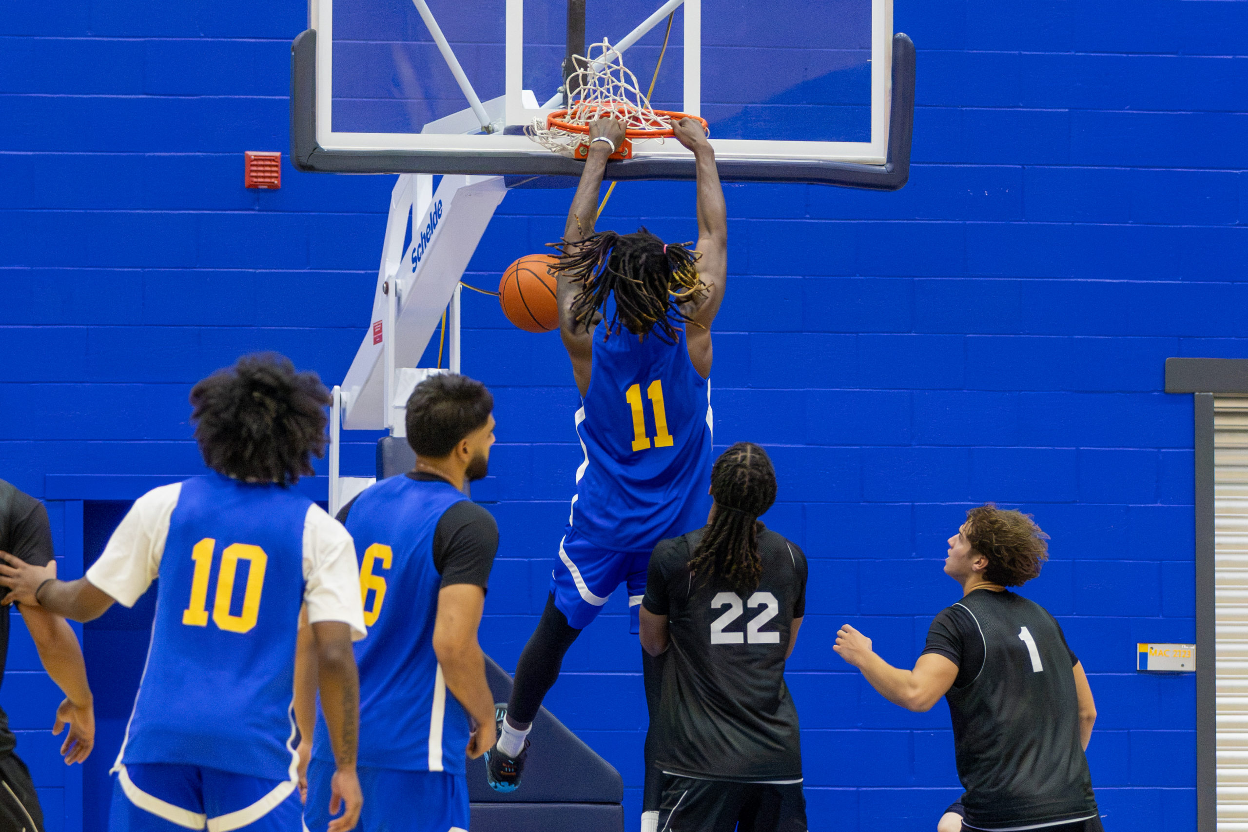 TMU player angrily dunks basketball while holding onto rim