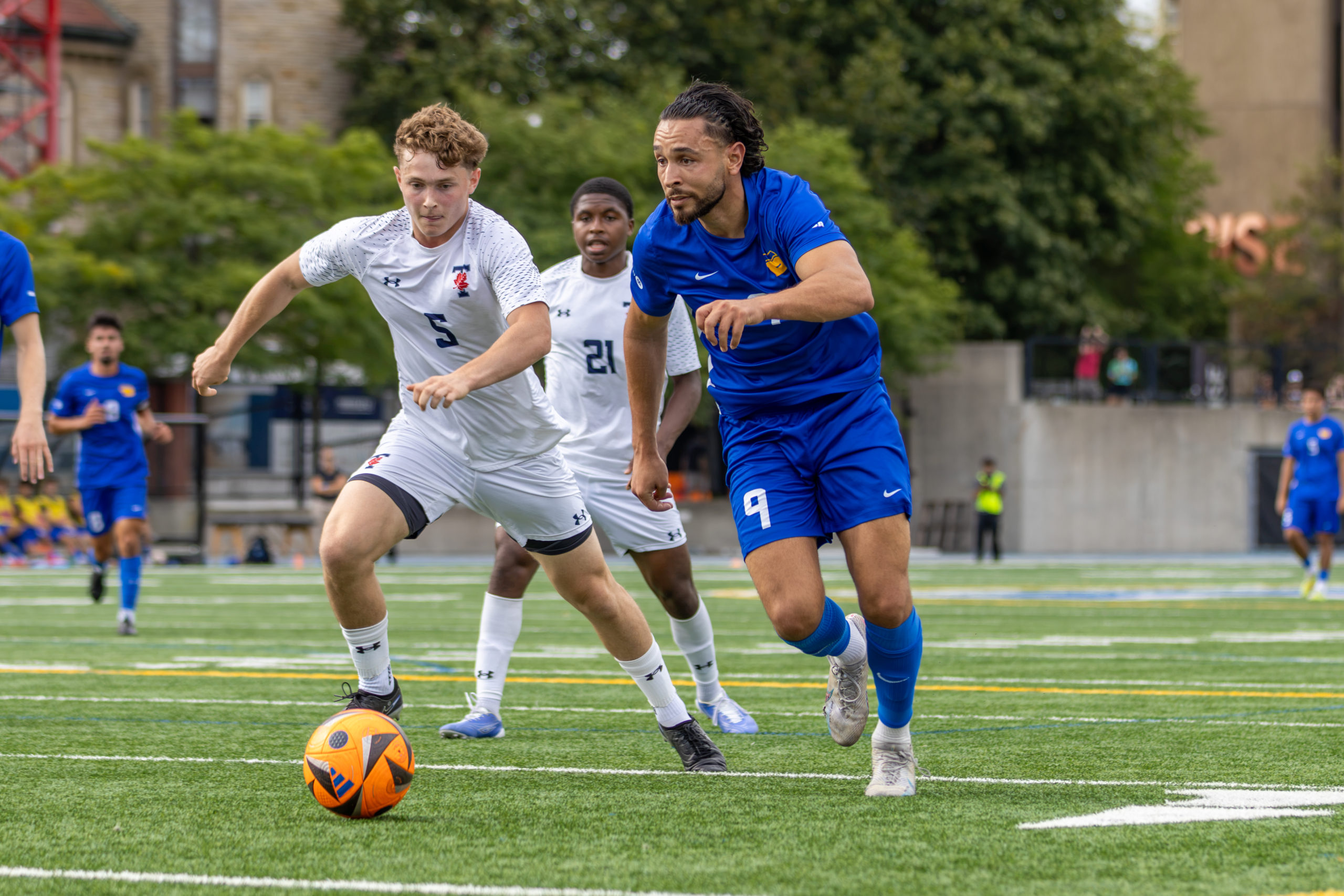 Varsity Blue and Bold player duel for the soccer ball.