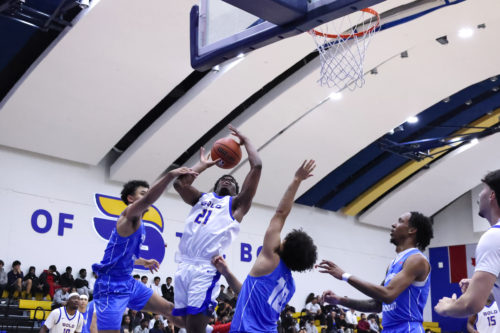 A TMU player shoots the ball as they're surrounded by three defenders
