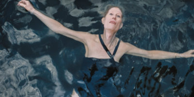 A still from the film Neverman. A women floats on her back in a body of water.