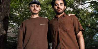 Portrait of two men looking at the camera while having each others arms on their shoulders.