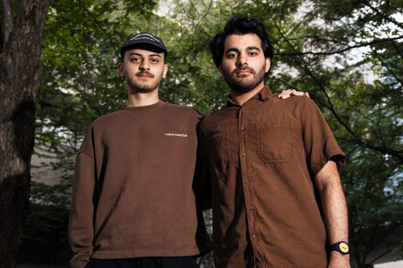 Portrait of two men looking at the camera while having each others arms on their shoulders.