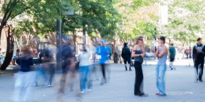 Students walk through campus in a motion blurred photo.