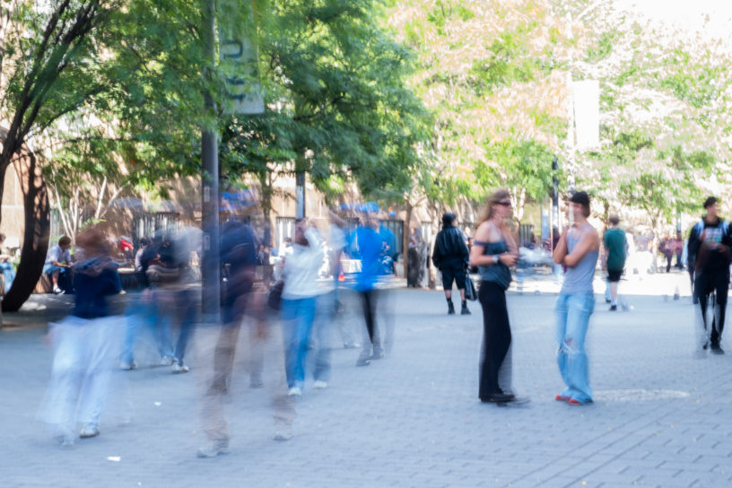 Students walk through campus in a motion blurred photo.
