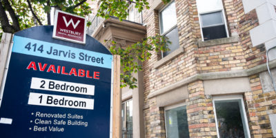 A photo of a sign in front of an apartment building listing available units.