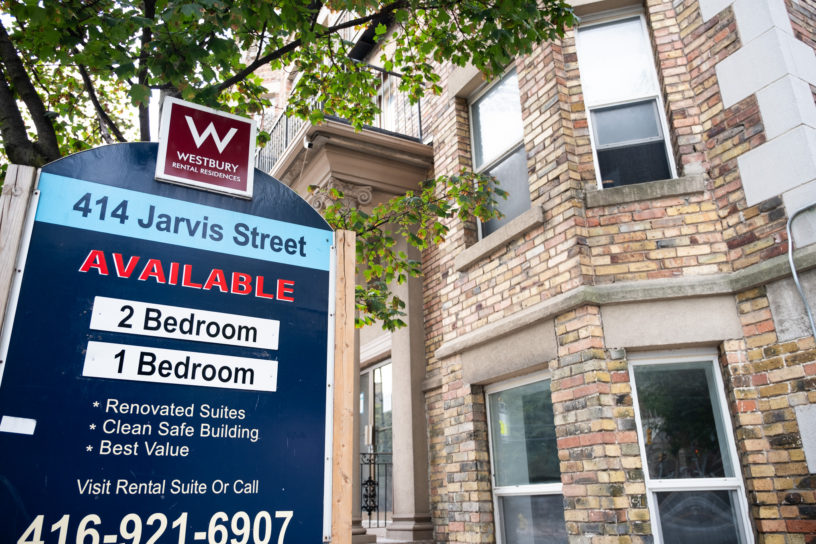 A photo of a sign in front of an apartment building listing available units.