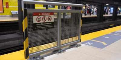 A grey fence is erected on a beige platform