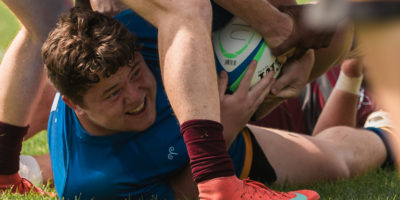 A picture of a man on the grass being wrestled for a ball.