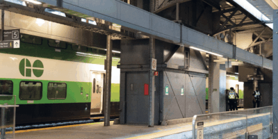 A GoTrain platform with a train on it, and some security guards standing on the platform in neon vests.