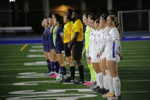 TMU Bold and U of T Varsity Blues women's soccer teams line up on the pitch