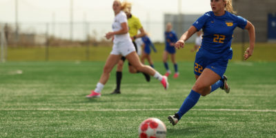 Soccer player chasing ball on pitch