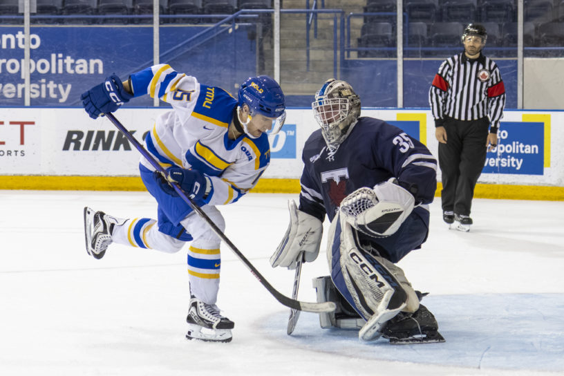 Bold men's hockey player, Carson Lloyd, tries to score a shootout winner against Blues goalie