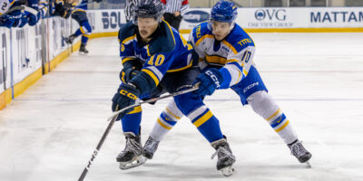 A TMU and a Lakehead hockey player fighting for the puck