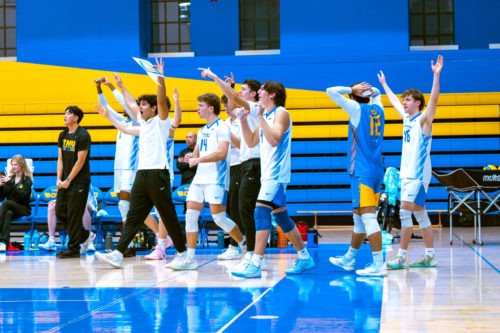 TMU men's volleyball team celebrates on the sidelines