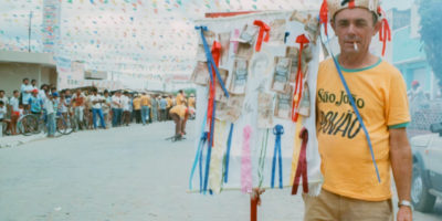 Photo of a man holding a sign with various ribbons and Brazilian reais.