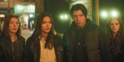 Photo of four people staring into the distance in a city-like environment.