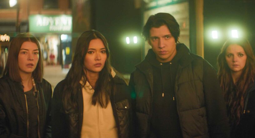 Photo of four people staring into the distance in a city-like environment.