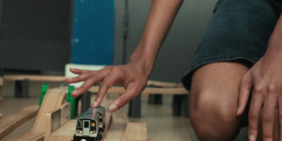Photo of hands playing with toy trains.