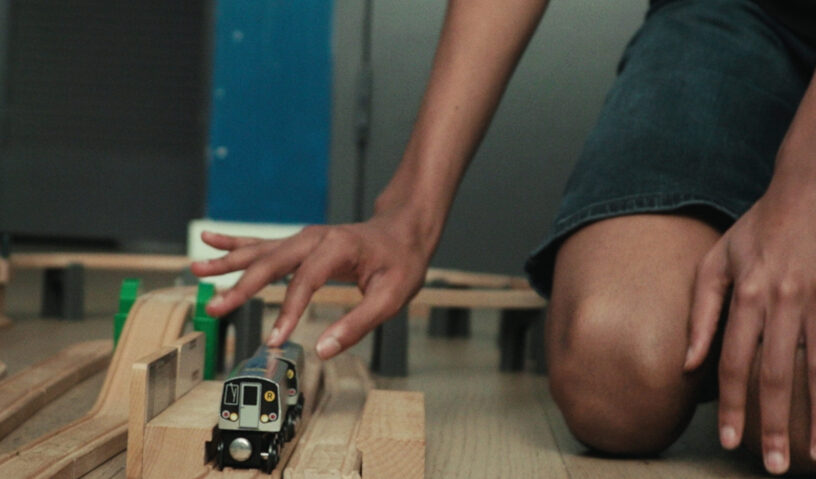 Photo of hands playing with toy trains.