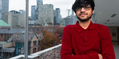 Photo of a person leaning against a window which looks out to a view of various buildings.