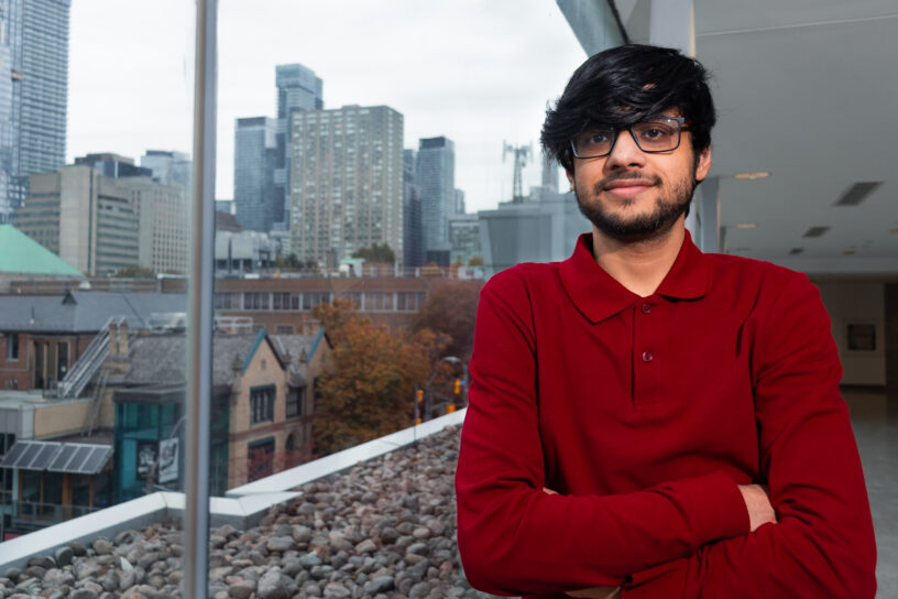 Photo of a person leaning against a window which looks out to a view of various buildings.