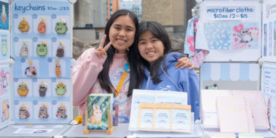 Two students man the booth of their small business at a market on Gould Street.