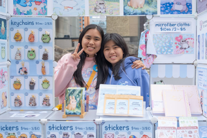 Two students man the booth of their small business at a market on Gould Street.