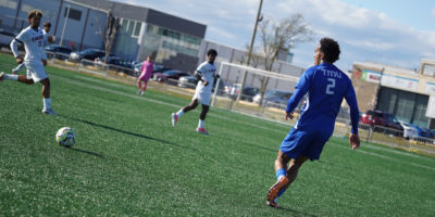 TMU soccer player approaches the ball against two Carleton defenders
