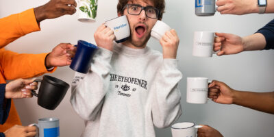 A boy is surrounded by hands with coffee mugs.