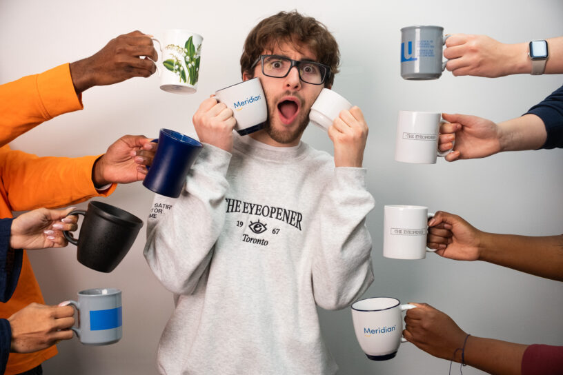 A boy is surrounded by hands with coffee mugs.