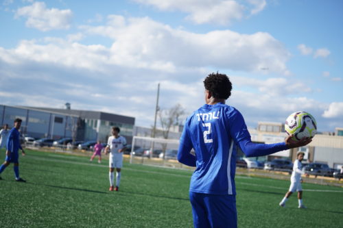 Bold soccer player holds a ball in their hand