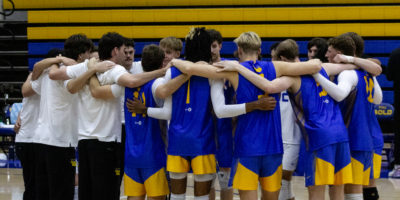 TMU men's volleyball team embraces on the court