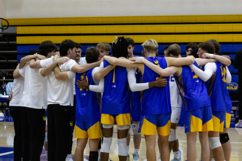 TMU men's volleyball team embraces on the court