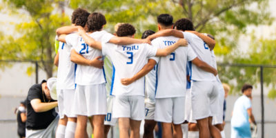 Men's soccer team embracing on the pitch