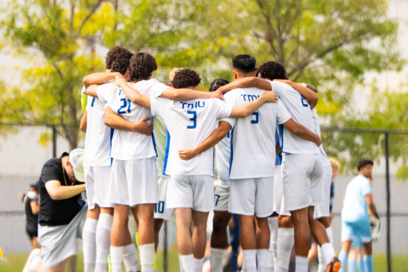 Men's soccer team embracing on the pitch