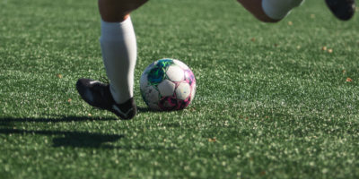 A person preparing to kick a soccer ball on the pitch