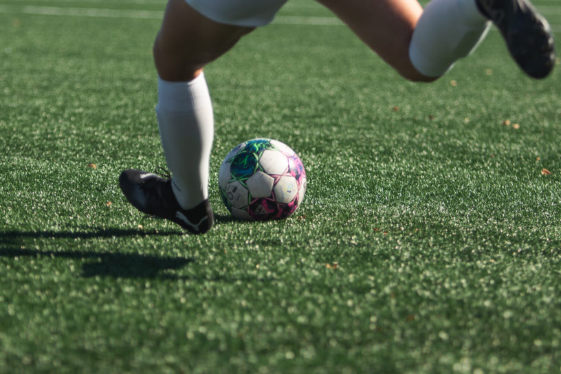 A person preparing to kick a soccer ball on the pitch